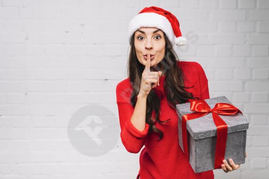 A young woman holding a gift box and showing a silent gesture, perfect for holiday or surprise-themed designs and content creation