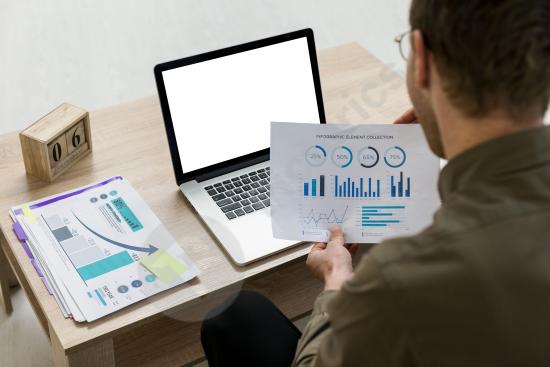 A man working with infographics and data visualizations in an office setting, ideal for business and technology-related content