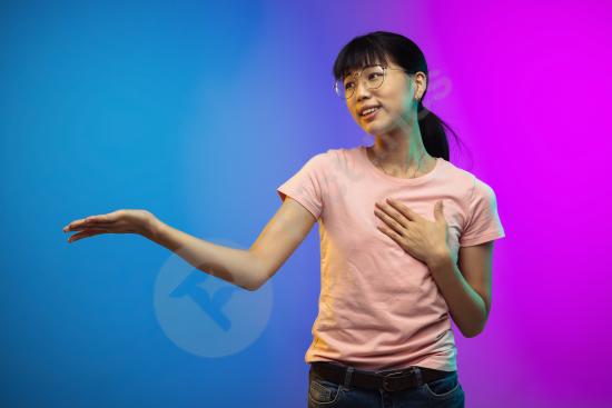 Portrait of a young Asian woman in a studio with a gradient-colored wall, capturing natural beauty and elegance