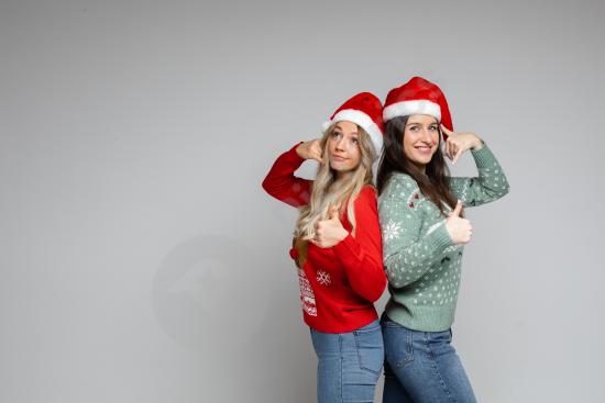 Group of friends wearing red and white Santa hats, smiling and recommending something, perfect for Christmas promotions and festive marketing.