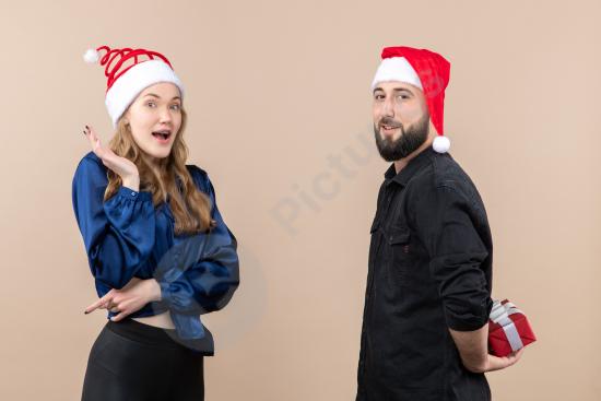Front view of a young woman as a man prepares to give her a gift against a pink background, perfect for romantic and celebration themes.