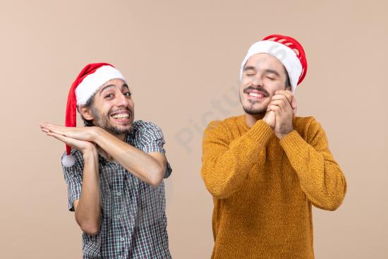 Front view of two happy boys wearing Santa hats, one clapping and the other making a wish, perfect for Christmas, holiday joy, and festive themes.