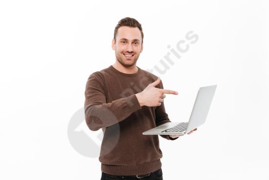 Smiling young man using a laptop and pointing, representing business presentation, communication, and modern digital work.