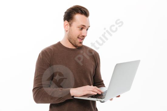 Excited young man using a laptop computer, expressing success, enthusiasm, productivity, and modern digital work lifestyle.