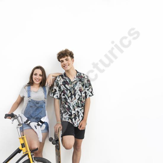 Portrait of a happy couple with a bicycle and skateboard, representing active lifestyle, outdoor fun, youth culture, and togetherness.