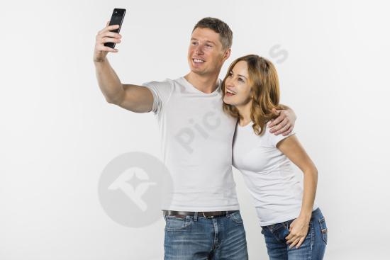Young couple taking a selfie with a mobile phone, representing connection, lifestyle, social media, and modern digital communication.