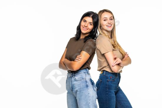 Portrait of two beautiful girls standing back to back on a white background, representing friendship, confidence, youth, and positive lifestyle.