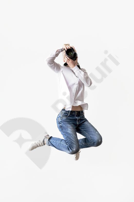 Energetic woman jumping while using her camera to take a photo, capturing movement and creativity, perfect for travel, lifestyle, and photography cont...
