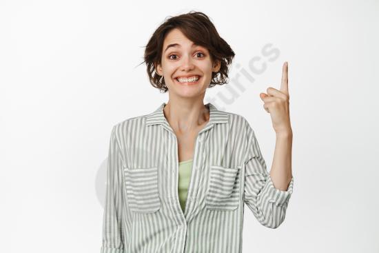 Portrait of an excited smiling woman pointing finger up, demonstrating an advertisement or click action, isolated on white background.