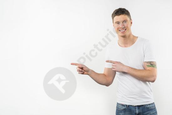 Portrait of a young man pointing finger while looking at the camera, isolated on white background, ideal for advertising and marketing concepts.