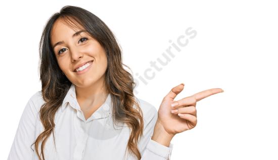 Young brunette woman wearing casual clothes, smiling with a big expression and pointing to the side while looking at the camera.