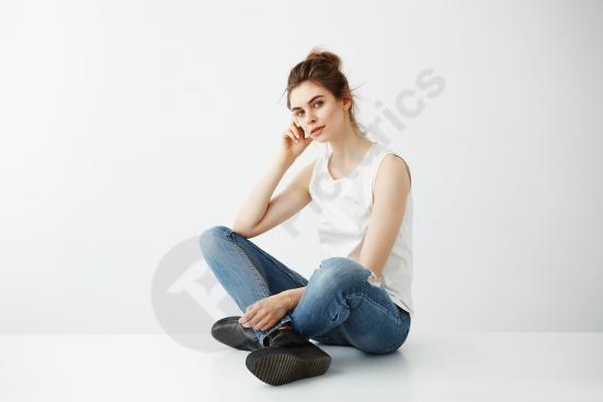 Young beautiful brunette woman with a hair bun smiling while sitting, isolated on a white background for lifestyle or portrait use.