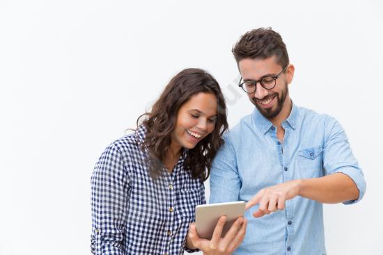 Cheerful couple watching content on a tablet and laughing together, representing entertainment, technology use, and shared lifestyle moments.