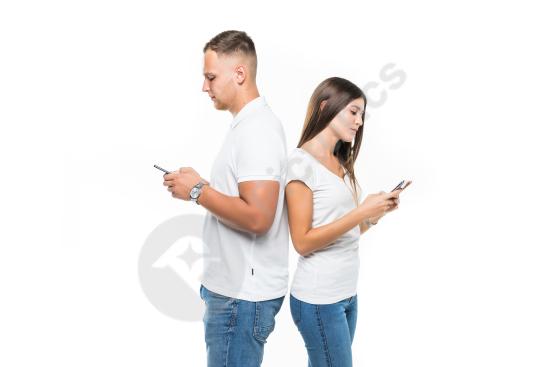 Beautiful couple standing back to back while using mobile phones, isolated on a white background, representing modern communication and lifestyle conc...