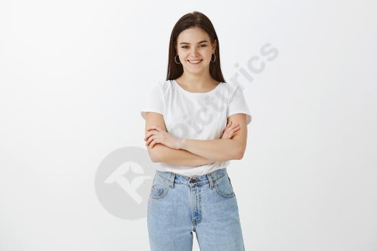 Happy young woman posing against a white wall with a natural smile, ideal for lifestyle, portrait, advertising, or modern design concepts.