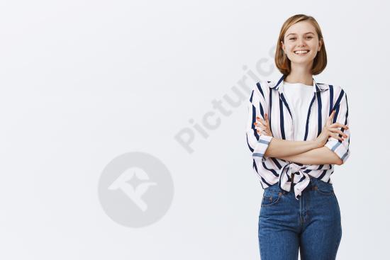 Confident young professional woman standing with arms crossed and smiling, representing success, leadership, career growth, and business confidence.