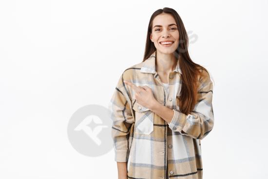 Smiling attractive woman pointing to copy space on the left, promoting a deal or advertisement, isolated on a white background for marketing use.