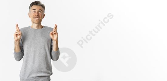 Excited hopeful middle-aged man crossing fingers for good luck, expressing a wish or anticipation, ideal for emotion, motivation, or concept-based des...