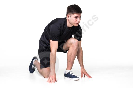 Full-length portrait of a male athlete in starting position ready to run, isolated on white background, concept of fitness, speed, and training.