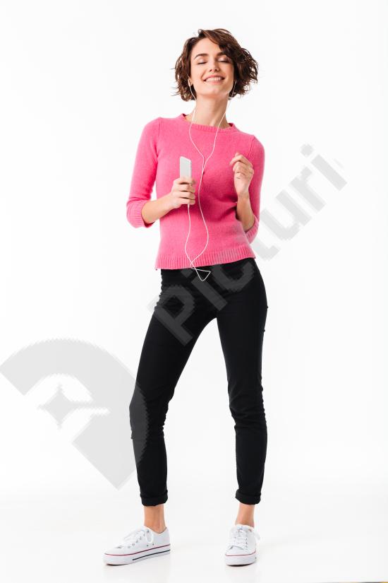 Full-length portrait of a happy girl listening to music with headphones, smiling and enjoying sound, isolated on a white background.
