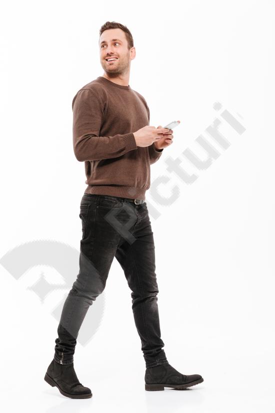 Concentrated young man chatting on a mobile phone. Modern communication concept with focused expression isolated on a clean background.