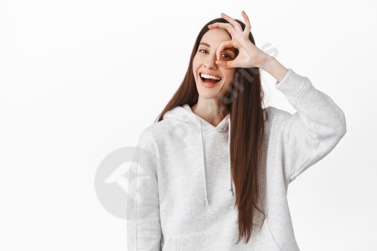 Positive young woman smiling and showing an OK gesture to express approval and satisfaction. Studio portrait perfect for success, agreement, and quali...