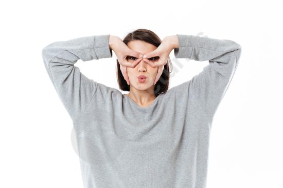 Young lady making a glasses shape with her hands on her face. Playful studio portrait perfect for fun, creativity, and imagination concepts.